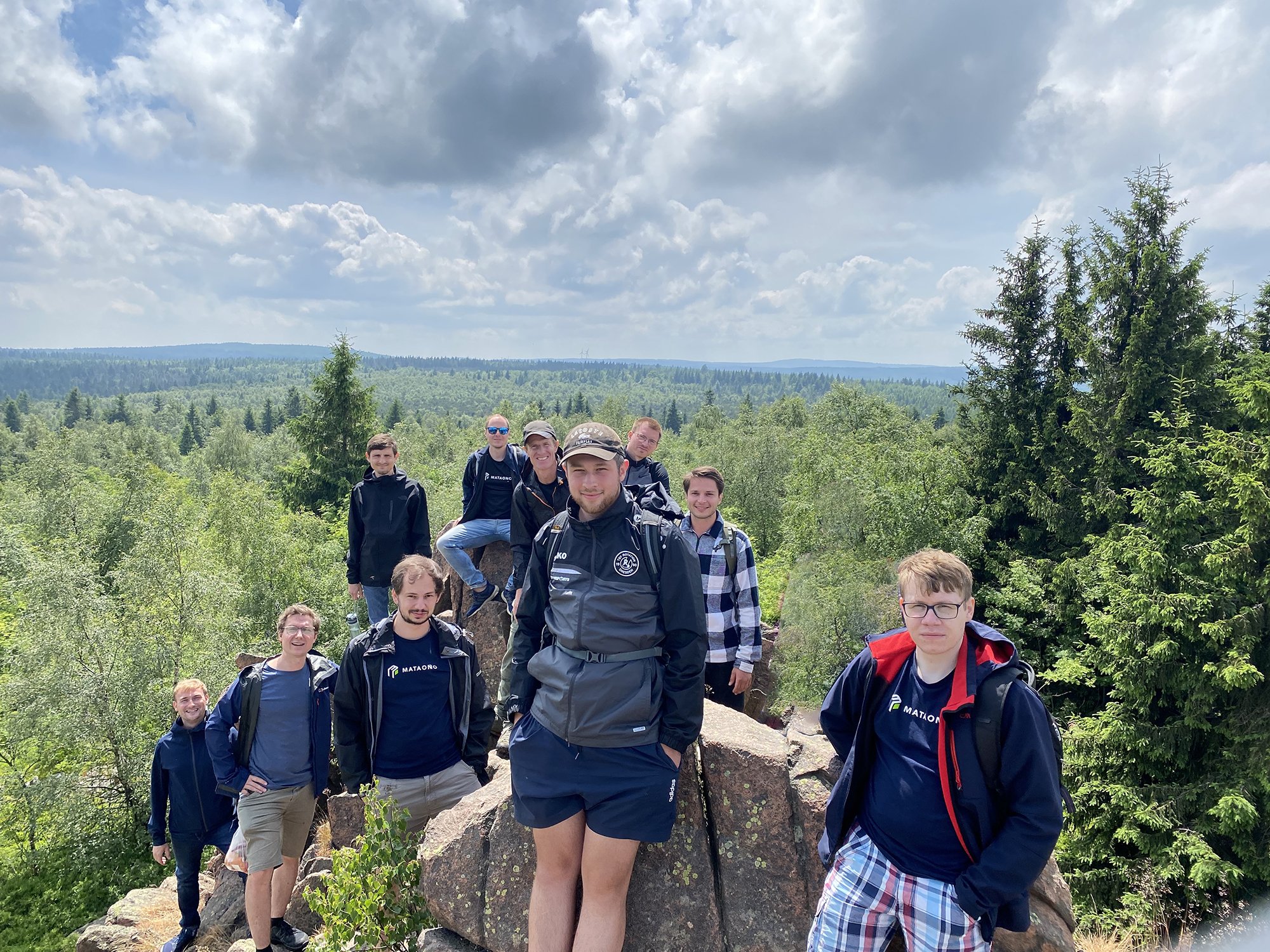 Team descript blickt von einem Berggipfel in die Kamera